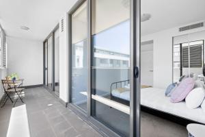 a bedroom with a balcony with a bed and sliding glass doors at NEW 3BR Apt in Kingsgrove Sleeps 7 in Sydney