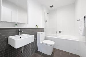a bathroom with a toilet and a sink and a tub at NEW 3BR Apt in Kingsgrove Sleeps 7 in Sydney