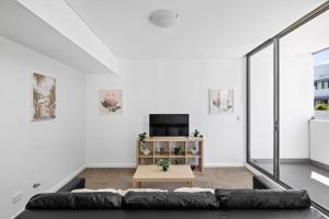 a living room with a couch and a tv at NEW 3BR Apt in Kingsgrove Sleeps 7 in Sydney