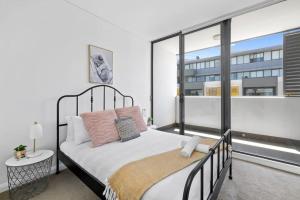 ein Schlafzimmer mit einem Bett und einem großen Fenster in der Unterkunft NEW 3BR Apt in Kingsgrove Sleeps 7 in Sydney