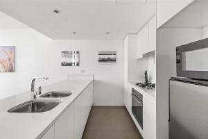 a white kitchen with two sinks and a microwave at NEW 3BR Apt in Kingsgrove Sleeps 7 in Sydney