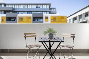 two chairs and a table with a potted plant on a balcony at NEW 3BR Apt in Kingsgrove Sleeps 7 in Sydney