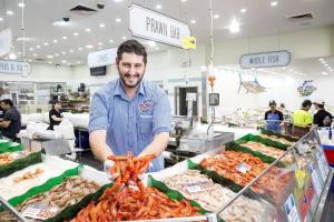a man standing in a market with a bunch of seafood at NEW 3BR Apt in Kingsgrove Sleeps 7 in Sydney