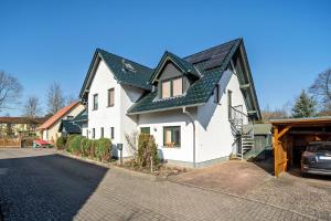 a white house with a black roof on a street at Reinhards Ferienwohnung in Greifswald