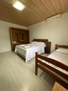 Un dormitorio con 2 camas y un banco. en Linda Casa Jardim - 500 Mts da Praia, en Navegantes