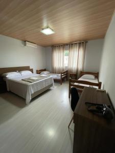 Habitación con 2 camas, mesa y escritorio. en Linda Casa Jardim - 500 Mts da Praia, en Navegantes
