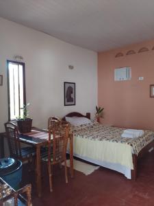 1 dormitorio con 1 cama, mesa y sillas en CHALE PERTO DA PRAIA COM DUAS SUITES E VARANDAO, en Pacatuba