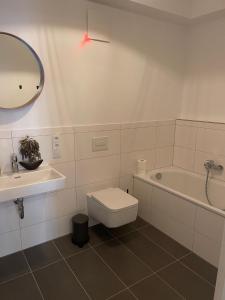 een badkamer met een toilet, een bad en een spiegel bij Wohlfühlen im Herzen von Wunstorf, 10min zum Meer in Wunstorf