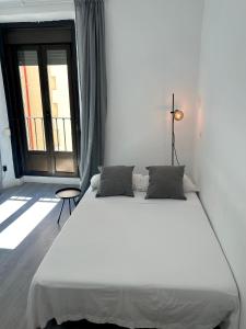 a white bed in a room with a large window at Centric 3ºI in Madrid