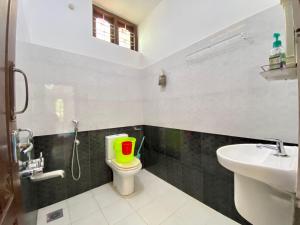 un bagno con servizi igienici con secchio verde e rosso di Mango Villa a Varkala