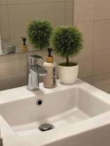 een wastafel in de badkamer met een fles zeep en een plant bij Relaxing Studio Unit in Taguig in Manilla