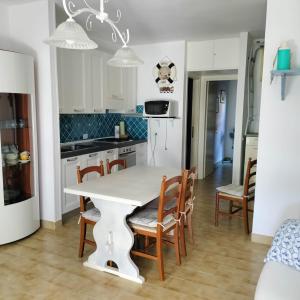 una cucina con tavolo e sedie bianchi di PM 22 Via Cala Sabina Guest House a Stintino