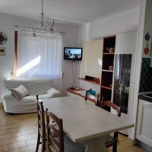 cocina y sala de estar con mesa y sofá en PM 22 Via Cala Sabina Guest House, en Stintino