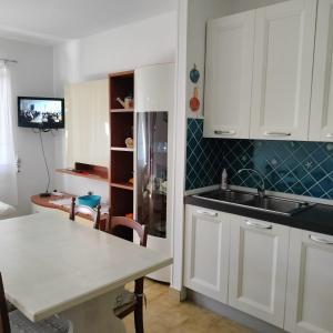 cocina con armarios blancos, fregadero y mesa en PM 22 Via Cala Sabina Guest House, en Stintino