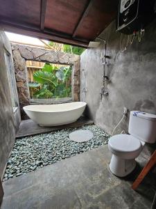 a bathroom with a bath tub and a toilet at UmaUthu Bali in Tabanan