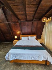 a bedroom with a large bed with a wooden ceiling at UmaUthu Bali in Tabanan