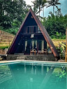 una casa con techo de paja junto a una piscina en UmaUthu Bali, en Tabanan
