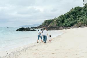 una familia caminando por la playa en Base in Onnason,Okinanawa ウォータサーバー,本格コーヒー,アメニティと設備充実,ベビー用品,おもちゃ完備,BBQ可能, en Onna