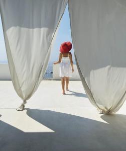 uma mulher de vestido branco e chapéu vermelho andando num barco em Salina Castel Vinci em Rinella