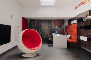 a living room with a red chair in a room at Designhotel Maastricht in Maastricht