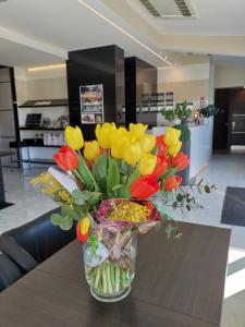 eine Vase voller gelber und roter Blumen auf einem Tisch in der Unterkunft Best Western Plus Hotel Modena Resort in Formigine