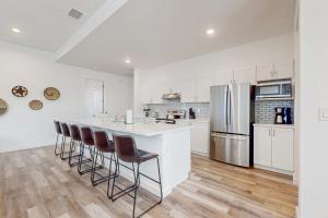 a kitchen with white cabinets and a counter with bar stools at Cove House in Matlacha
