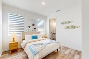 a white bedroom with a bed and a surfboard on the wall at Cove House in Matlacha