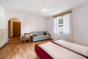 1 dormitorio con 1 cama y 1 sofá en Fröhlichhof Wohnung Apfelblüte, en Lagundo