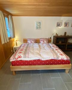una camera con un letto e un piumone rosso e bianco di 1 room apt, kitchen, patio, in beautiful chalet a Les Diablerets