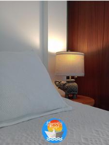 1 cama con edredón blanco y mesa con lámpara en ALOJAMIENTOS ROSARIO! MONOAMBIENTE TELLIER a media cuadra del Boulevard Oroño en Rosario