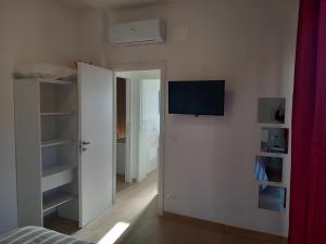 a bedroom with a tv on the wall and a door at Milly Rooms in Celle Ligure