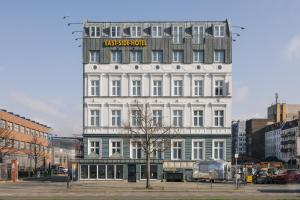 a tall white building with a sign on it at Homaris East Side Hotel - Mobile Key Access in Berlin