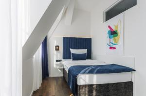 1 dormitorio con 1 cama con manta azul en Homaris East Side Hotel - Mobile Key Access, en Berlín