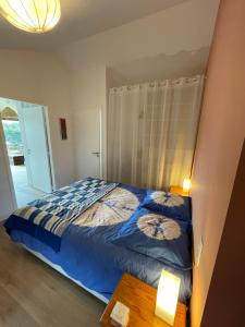a bedroom with a bed with a blue comforter at Samui in Capbreton