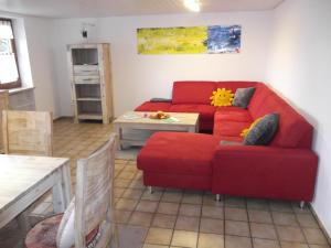 ein Wohnzimmer mit einem roten Sofa und einem Tisch in der Unterkunft FEWO 4 am Rechensöldenweg 29 in Bodenmais