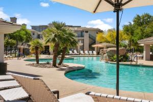 a swimming pool with chairs and an umbrella at CozySuites Oasis at Kierland Commons in Scottsdale