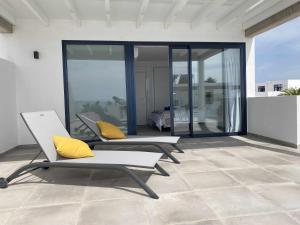 2 Stühle mit gelben Kissen auf einer Terrasse in der Unterkunft Aguja, Villa con piscina y barbacoa para disfrutar in Puerto Calero