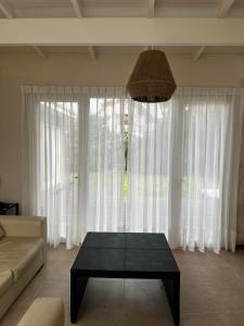 a living room with a coffee table in front of a large window at Casa Juno Pinamar Norte in Pinamar