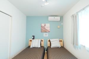 two beds in a room with blue walls at Base in Onnason,Okinanawa ウォータサーバー,本格コーヒー,アメニティと設備充実,ベビー用品,おもちゃ完備,BBQ可能 in Onna