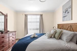 a bedroom with a large bed with pillows and a dresser at Beautiful Home In Milperra Sleeps 8 in Sydney