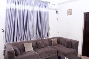 a living room with a brown couch in front of a window at Ms Cynthia in Lagos