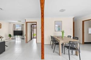 una sala da pranzo con tavolo, sedie e TV di Beautiful Home In Milperra Sleeps 8 a Sydney
