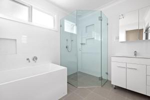 baño blanco con ducha y lavamanos en Beautiful Home In Milperra Sleeps 8 en Sídney