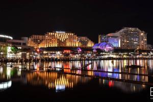 una città illuminata di notte con edifici e acqua di Beautiful Home In Milperra Sleeps 8 a Sydney