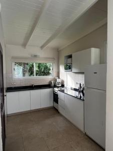 a large kitchen with white cabinets and a window at Casa Juno Pinamar Norte in Pinamar