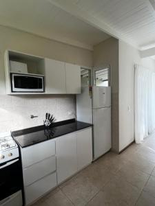 a kitchen with white cabinets and a stove and a microwave at Casa Juno Pinamar Norte in Pinamar