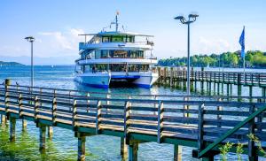 a boat is docked next to a pier at Ferienhaus Sisi - Moderner Neubau im Grünen, nahe See, S-Bahn und mit E-Ladesäule in Pöcking