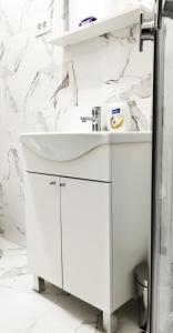 a bathroom with a white sink and marble walls at Blue Skies in Podgorica +3 photos