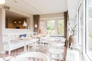 a restaurant with white tables and white chairs at Aarskogs Boutique Hotel in Glücksburg