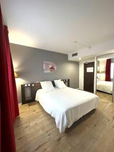 1 dormitorio con 1 cama grande con sábanas blancas en Hôtel Le Cousture en Toulouse